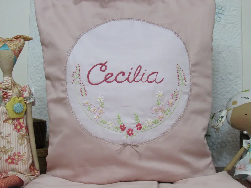 Quillow rosa com o nome Cecília e pequenos ramos bordados.
