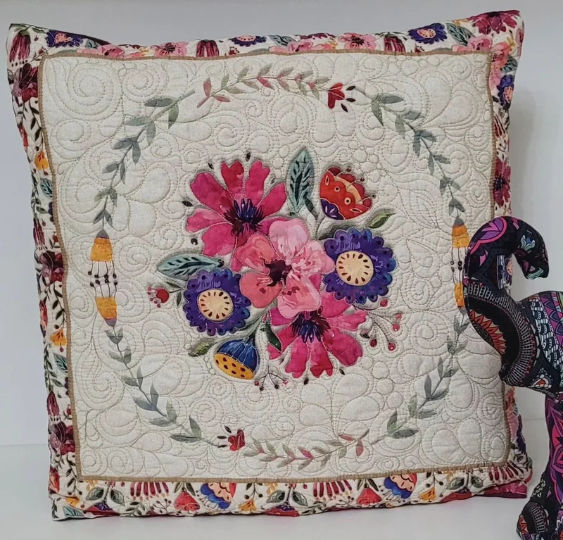 Quillow com flores coloridas e quilting sobre tecido claro.