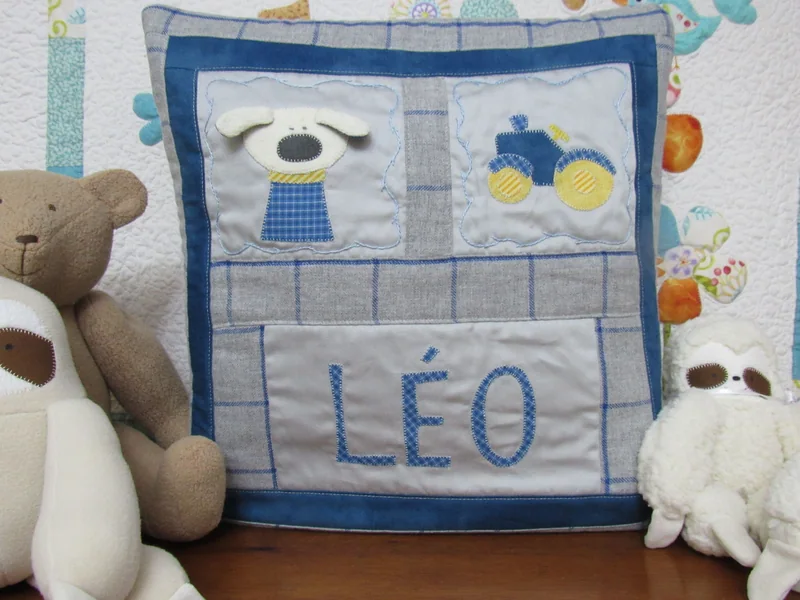 Quillow azul com aplicações de cachorro e trator e o nome Léo.
