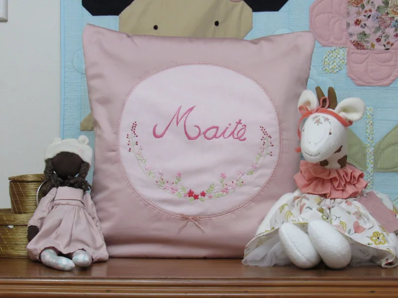 Quillow rosa com o nome Maitê e pequenos ramos bordados.