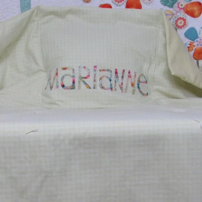Nome Marianne aplicado na manta clara.