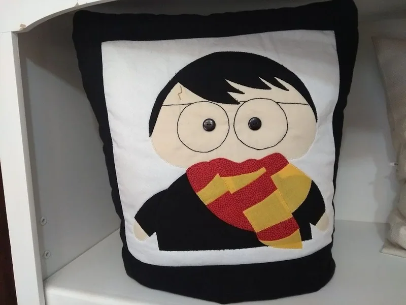 Quillow com personagem de óculos, cabelo preto e cachecol vermelho e amarelo.