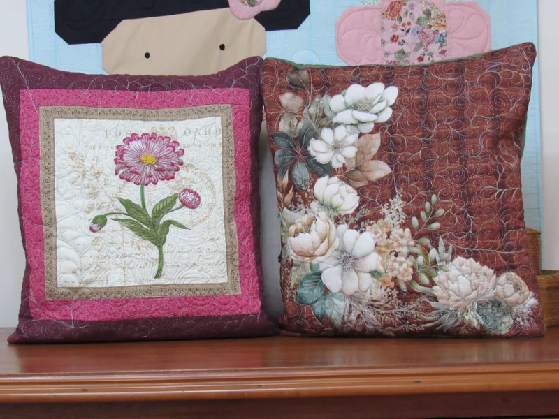 Dois quillows florais lado a lado, um com uma flor rosa e outro com grandes flores claras.