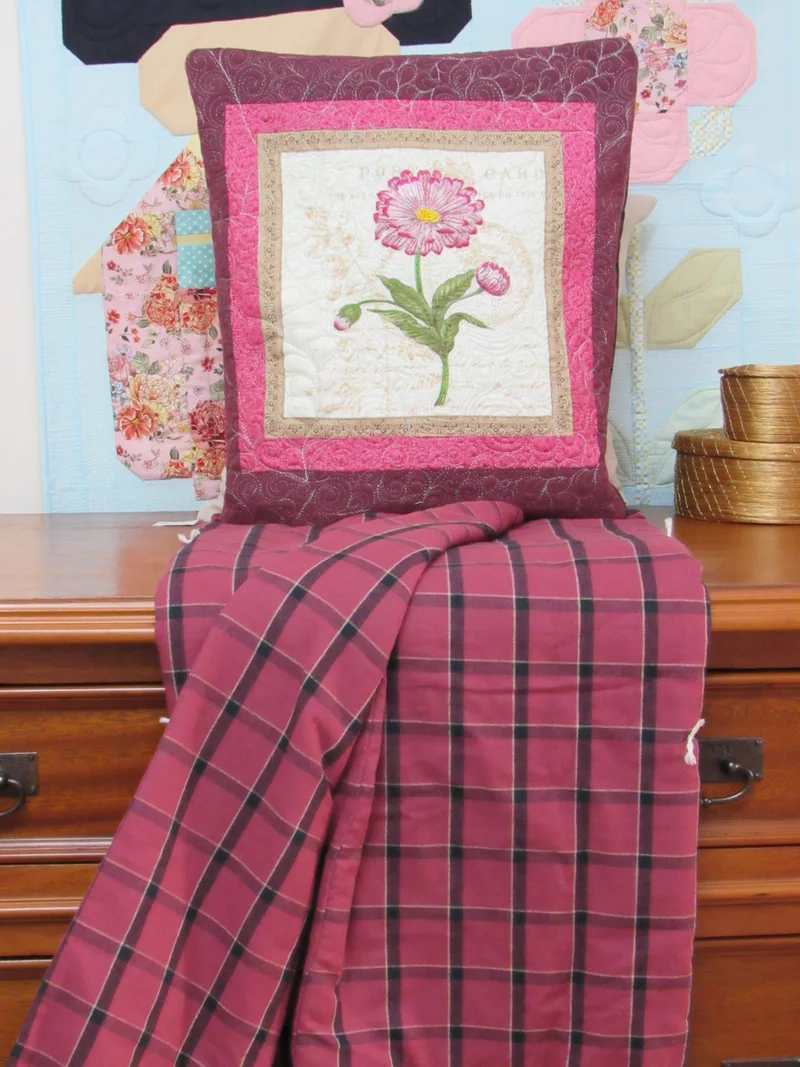Quillow de flor rosa com a manta xadrez rosa e vinho aberta.