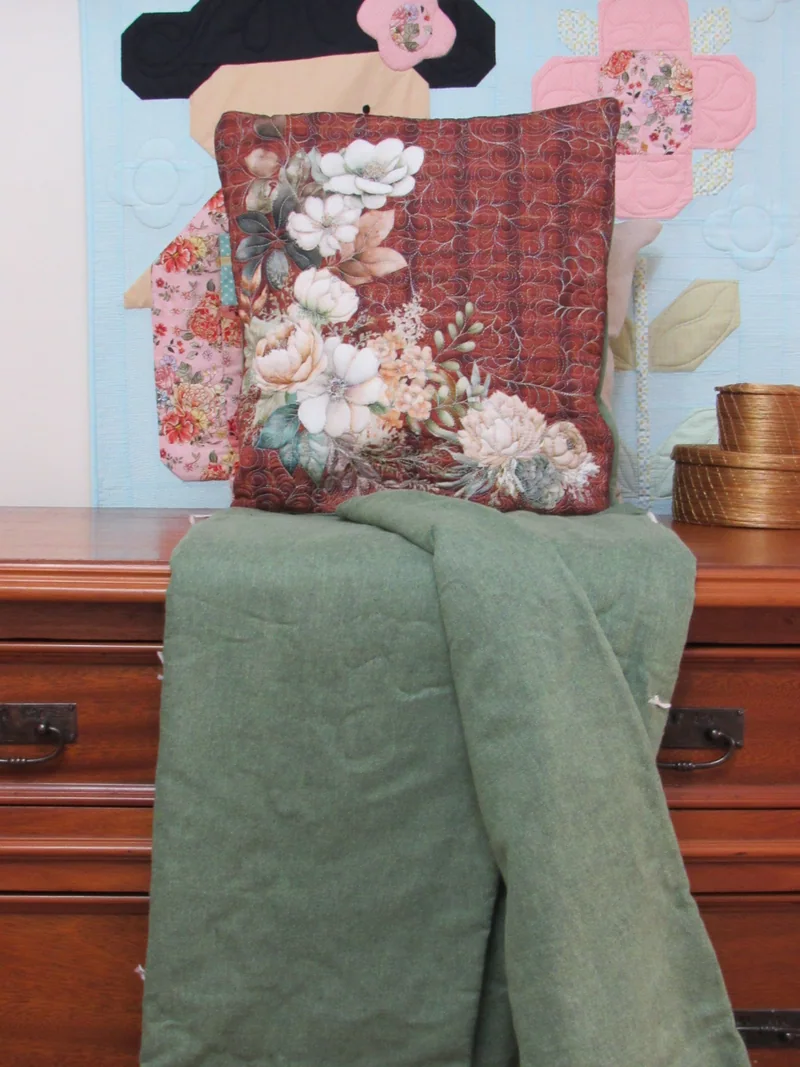 Quillow de flores claras com a manta verde aberta.