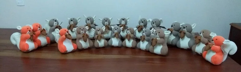 Raposas de tecido em laranja, cinza e diferentes estampas, reunidas em uma fileira.