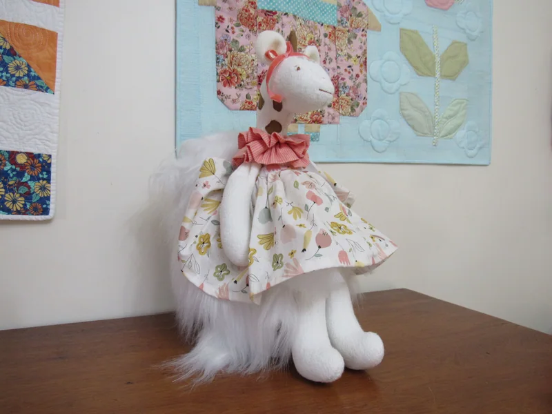 Ratinha branca em pé, com vestido floral claro e gola coral.
