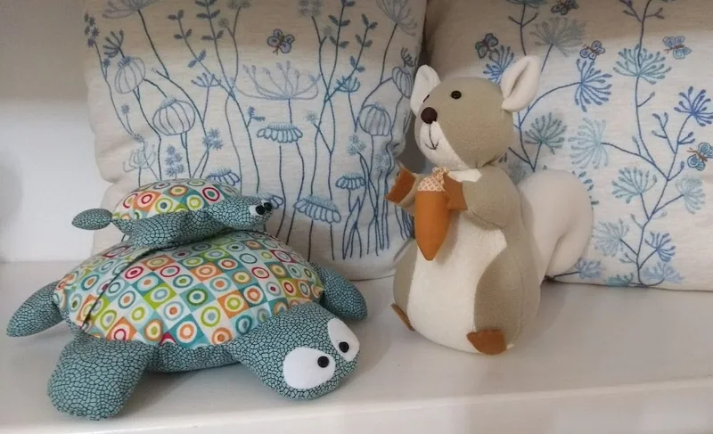 Duas tartarugas de tecido estampado e um esquilo com cauda branca.
