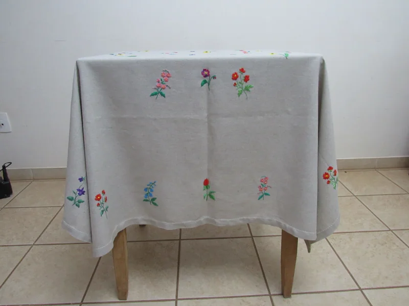 Toalha com bordados de flores vista pela lateral da mesa.